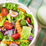 Colorful fresh vegetable salad with cherry tomatoes in a white bowl.